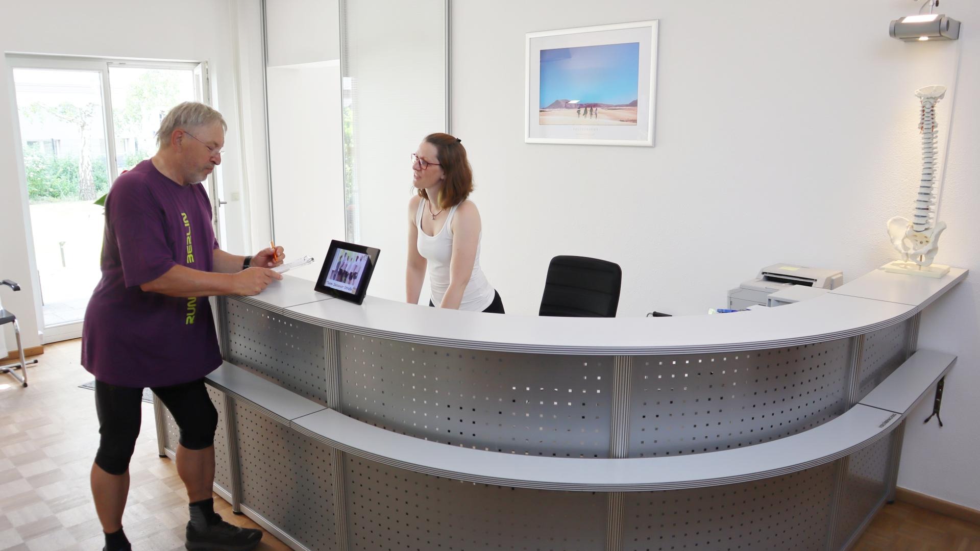 Ein Patient unterhält sich am Empfangstresen